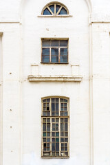 The facade of an old building of light color with high windows