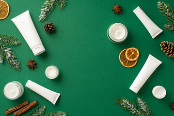 Fototapeta na wymiar Winter season skincare products concept. Top view photo of jars with cream tubes fir branches in frost cinnamon sticks pine cones dried orange slices on isolated green background with copyspace