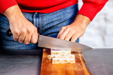 Crop man cutting nut nougat with knife