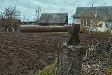 Old rusty axe with wooden handle stuck in the stump Large ax in hand