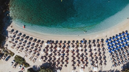 Aerial view of Sarakiniko Beach with turquoise sea and aligned beach umbrellas in Greece