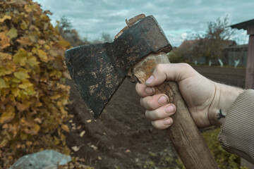 Old rusty axe with wooden handle stuck in the stump Large ax in hand