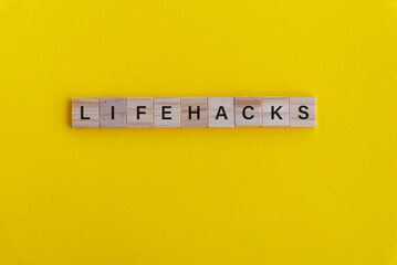 Life hacks spelling on wood block on yellow background