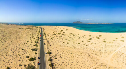 Mid level aerial panoramic view of the road through the sand dunes of the Parque Natural near Flag Beach Grandes Playa Corralejo in Fuerteventura Canary Islands