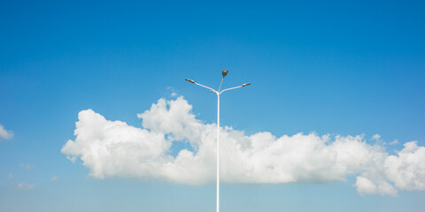 high lampposts with blue sky and white clouds on the background