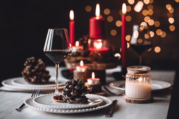 Rustic table decor for Christmas or New Year family dinner. Centrepiece with red candle, dry orange, cone, cinnamon, anise. Zero waste eco-friendly home. Cozy atmosphere, dark background. Close up
