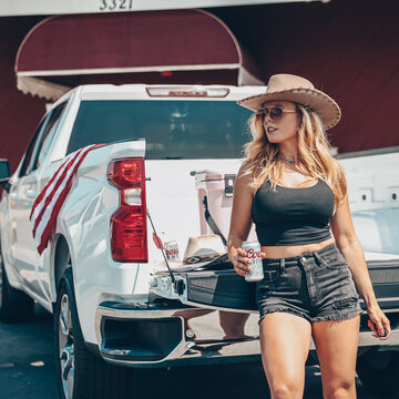 American Patriotic Blonde Girl Drinking Beer with White Pickup Truck and Boots