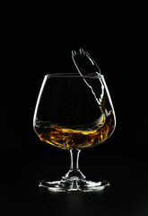 A splash of cognac in a glass on a black background