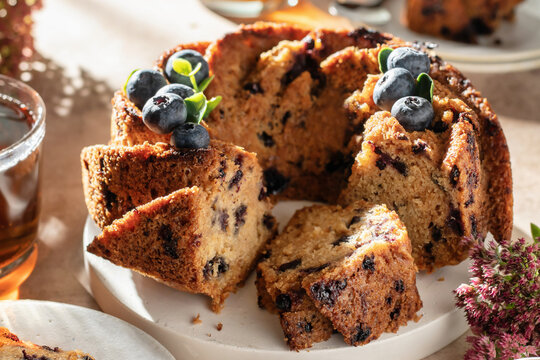 Sliced Blueberry Bundt Cake decorated with berries for tea close up, sunny morning festive breakfast concept, tea time