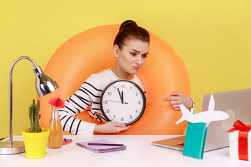 Sad upset woman in rubber ring on neck, showing wall clock to laptop screen, has video call, has no...