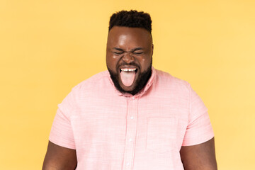 Portrait of man wearing pink shirt sticking out tongue and looking at camera, teasing with naughty...
