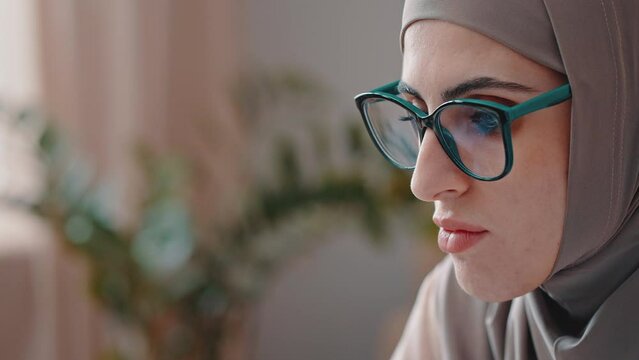 Young Arabian woman in glasses works on computer attentively