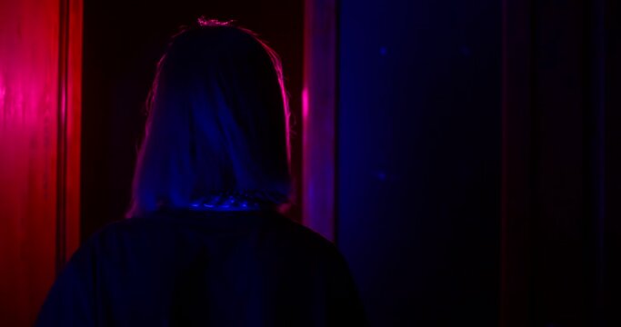 Brave girl stands in front of the door in the dark corridor in abandoned building. She looks around, abruptly opens the door and freezes in fright. Real-time quest attraction. Pursuit-concept.