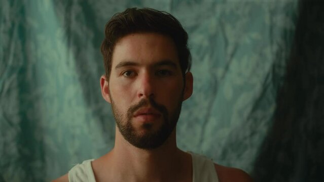 Young caucasian male wearing a white undershirt staring at the camera