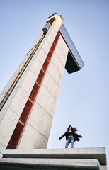 young latin woman wearing glasses fur jacket and blue pants dancing happy and relaxed next to the concrete building