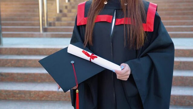 Master's hat and graduation diploma about higher education are in the female graduate's hands
