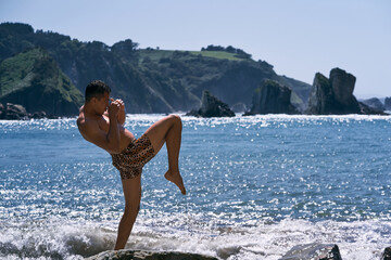 latin young man wearing a tiger trunks in profile with his arms folded doing wet martial art...