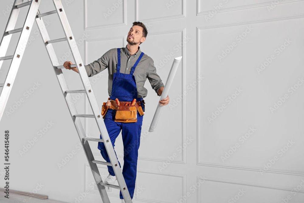 Poster Electrician in uniform with ceiling lamp on metal ladder indoors