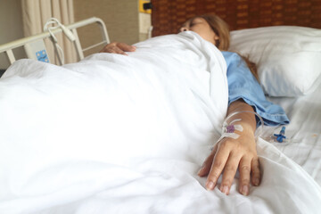 Focus on the hand of a patient in hospital ward, woman sleep on bed