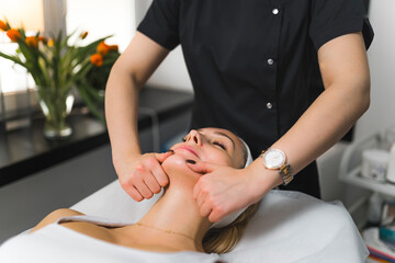 Obraz na płótnie Canvas Japanese face-lift massage. Beautiful caucasian woman enjoying her spa treatment. Mindfulness and relaxation concept. Modern beauty salon treatments. High quality photo
