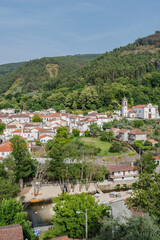 Fototapeta na wymiar Architecture of the village with houses, church and trees with river beach of Peneda in aerial view and mountain in the background, Góis PORTUGAL