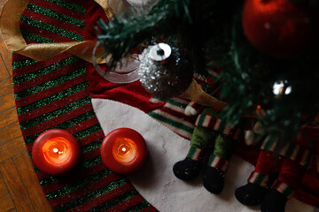 Burning candles on Christmas decorations at the foot of a Christmas tree decorated with spheres
