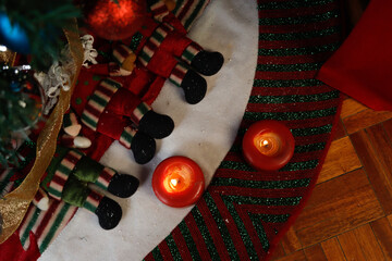 Burning candles on Christmas decorations at the foot of a Christmas tree decorated with spheres
