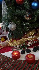 Burning candles on Christmas decorations at the foot of a Christmas tree decorated with spheres