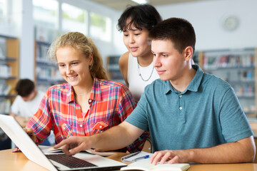 Schoolchildren help each other solve the task in school library. High quality photo