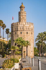 Fototapeta na wymiar Pot flowers and palm trees in front of the facade wall of the old watchtower Torre del Oro, Seville SPAIN