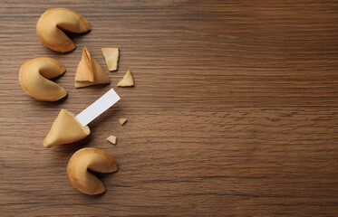 Tasty fortune cookies and paper with prediction on wooden table, flat lay. Space for text
