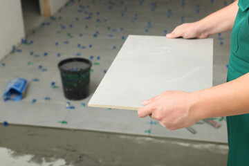 Fototapeta na wymiar Worker holding tile near adhesive mix on floor, closeup