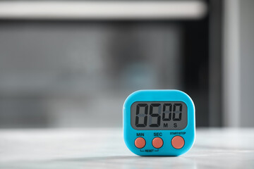 Kitchen timer on light grey table against blurred background. Space for text