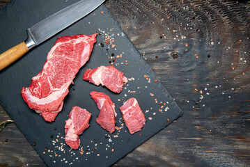 Raw organic meat ( beef or lamb ) on a dark slate, metal, stone or concrete background. Top view with copy space. - Powered by Adobe