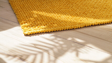 Soft mustard color bath mat on wooden floor indoors, closeup