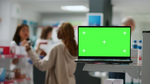 Display with isolated greenscreen template on laptop put on pharmacy shelves with medicaments and drugs, blank mockup background. Chroma key copyspace screen in pharmaceutics retail store.