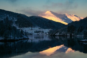 Schöne Aussicht auf einen See, umgeben von baumbedeckten schneebedeckten Bergen unter einem klaren blauen Himmel