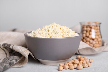 Chickpea flour in bowl and seeds on light grey table