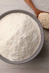 Ceramic bowl with quinoa flour and seeds on wooden table, top view