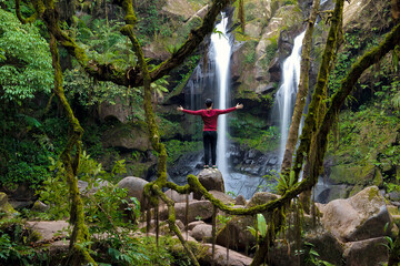 Man overlooking and showing two hand or happy and relaxing on sapan waterfall in khun nan national park  at Nan Province, Thailand.