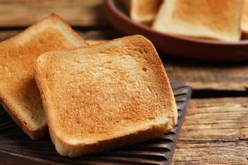 Slices of tasty toasted bread on wooden table, closeup