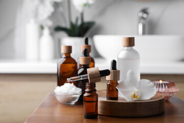 Fototapeta na wymiar Essential oils, orchid flower and sea salt on wooden table in bathroom