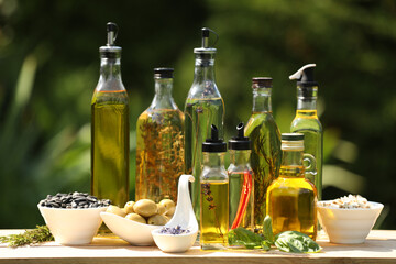 Different cooking oils and ingredients on wooden table against blurred green background