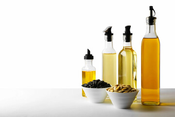 Bottles of different cooking oils and seeds on white background, space for text