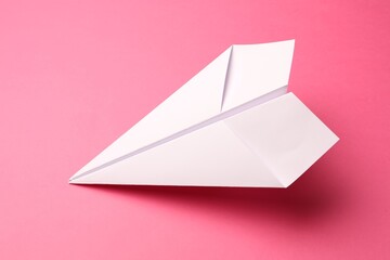 Handmade white paper plane on pink background