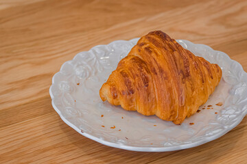 French croissant  and bread crumbs on white dish.
