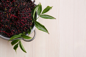 Tasty elderberries (Sambucus) on wooden table, top view. Space for text