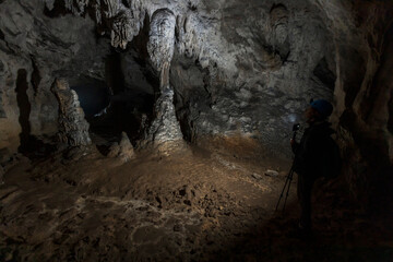 Speleologist Admiring with Help of a Light Stalactites and Stalagmites in Underground World