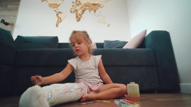 broken leg. A little girl paints on a plaster cast. Bone fracture. 