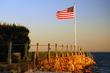 An American flag waves at the end of a jetty jutting out into the sea from an estate on the Fourth...